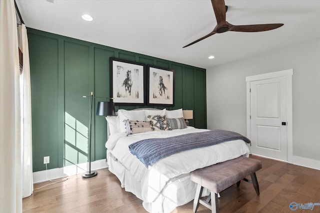 bedroom with ceiling fan, recessed lighting, wood finished floors, and a decorative wall