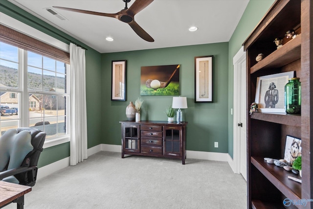 office space with light carpet, a ceiling fan, visible vents, and baseboards