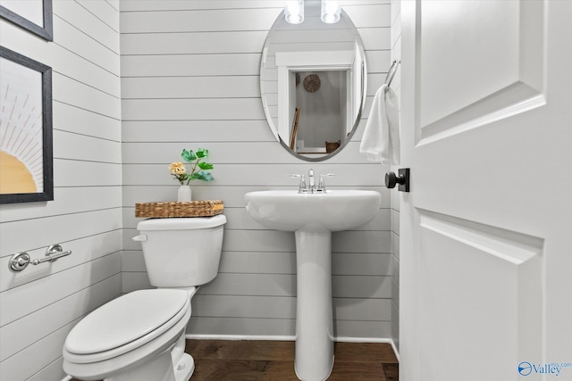 half bath with baseboards, toilet, and wood finished floors