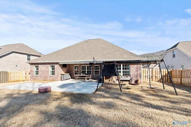 rear view of property with a patio area, a fenced backyard, a shingled roof, and brick siding