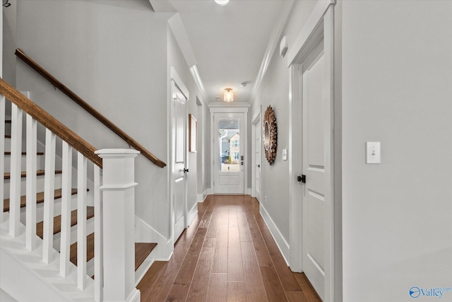 doorway featuring crown molding, stairway, baseboards, and wood finished floors