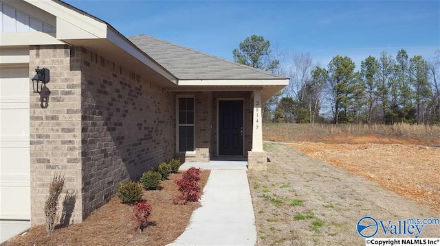 entrance to property featuring brick siding and a garage