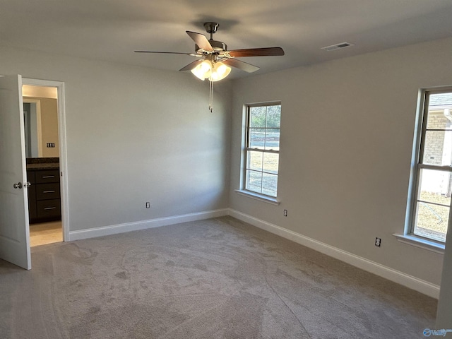 unfurnished bedroom with light colored carpet, visible vents, ensuite bathroom, and baseboards