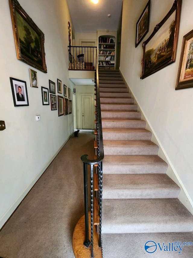 staircase featuring carpet flooring and a high ceiling