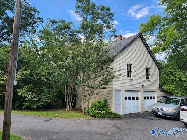 view of home's exterior featuring a garage and a chimney