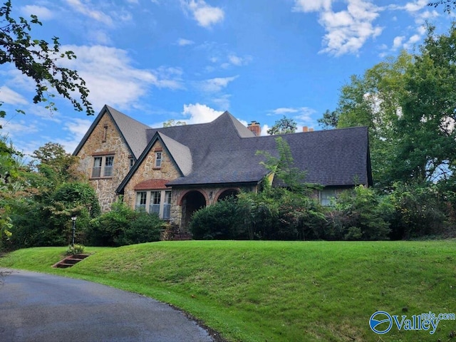 tudor home with a front lawn and a chimney