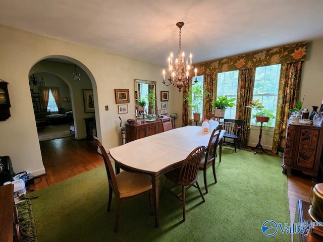 dining area featuring baseboards, arched walkways, a chandelier, and wood finished floors