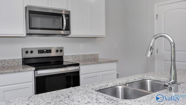 kitchen with stainless steel appliances, white cabinetry, and a sink