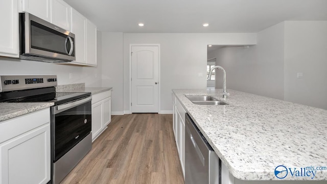 kitchen with stainless steel appliances, light wood-style floors, white cabinets, and a sink