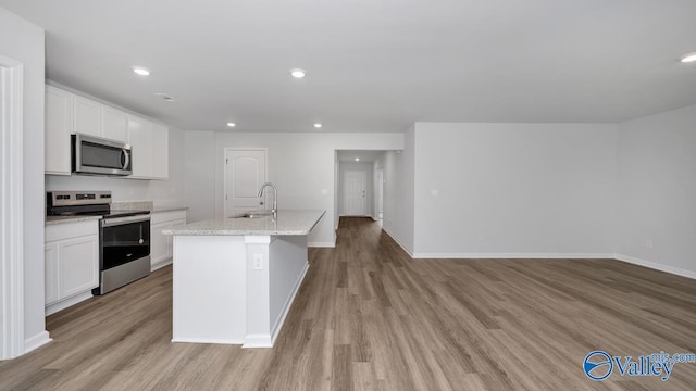 kitchen with white cabinets, appliances with stainless steel finishes, light wood-style floors, a sink, and recessed lighting