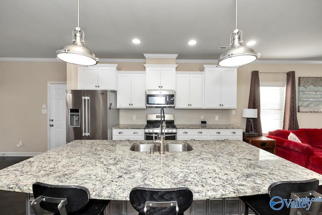 kitchen featuring a center island with sink, a breakfast bar, appliances with stainless steel finishes, ornamental molding, and white cabinets