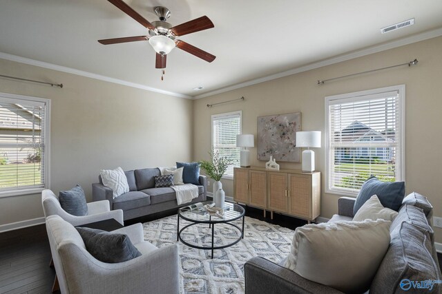 living room with ornamental molding, dark wood-type flooring, ceiling fan, and a healthy amount of sunlight