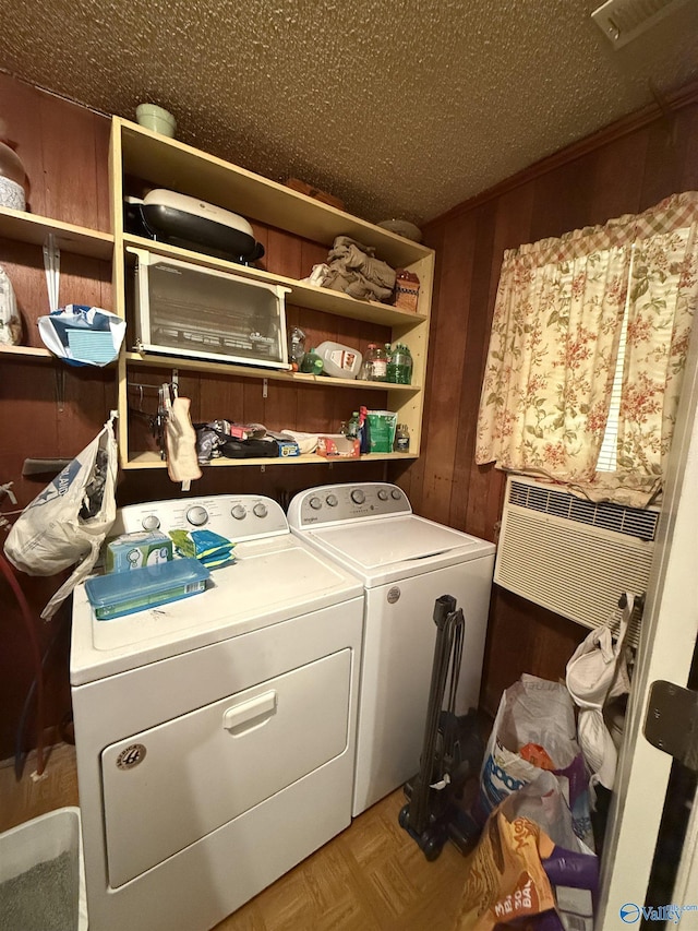 washroom with independent washer and dryer, wooden walls, a textured ceiling, and light parquet floors