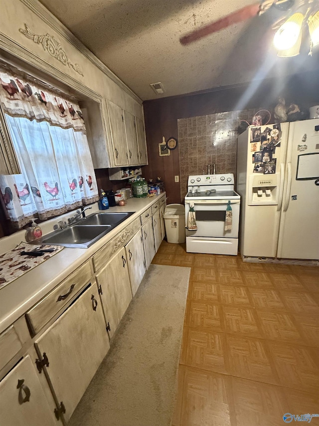 kitchen with sink, white appliances, ceiling fan, light parquet flooring, and a textured ceiling