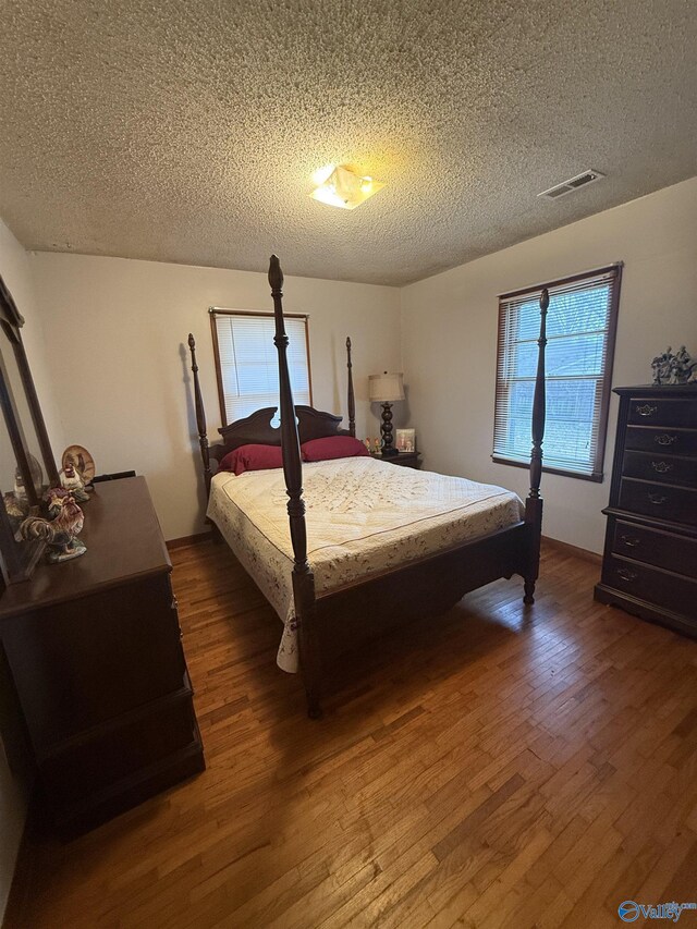 bedroom with dark hardwood / wood-style flooring and a textured ceiling