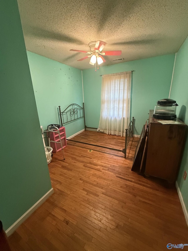 unfurnished bedroom with ceiling fan, hardwood / wood-style floors, and a textured ceiling