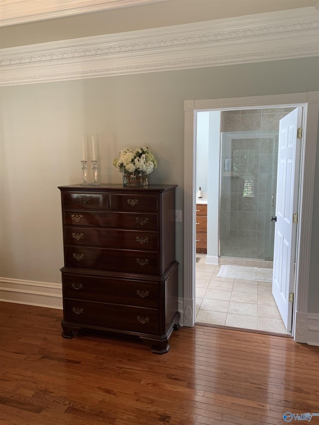 interior space featuring crown molding, wood-type flooring, a shower stall, and baseboards