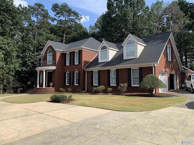 view of front of house featuring brick siding, an attached garage, a front yard, a balcony, and driveway