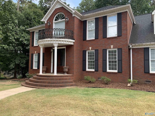 view of front of property featuring brick siding, a shingled roof, a front yard, crawl space, and a balcony