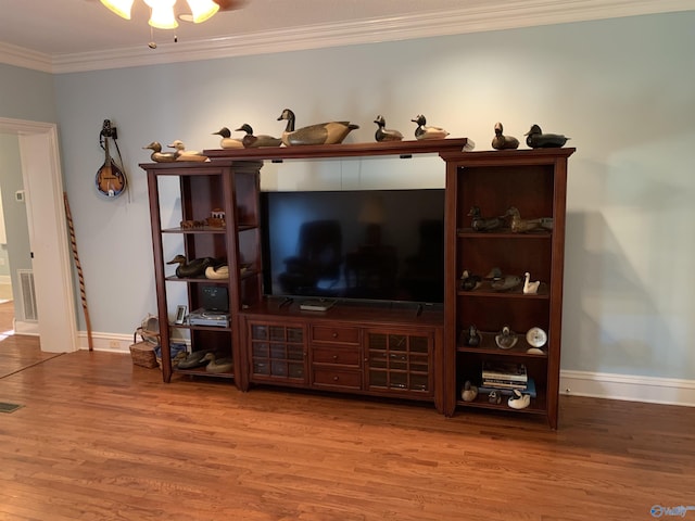 living room with ornamental molding, visible vents, baseboards, and wood finished floors