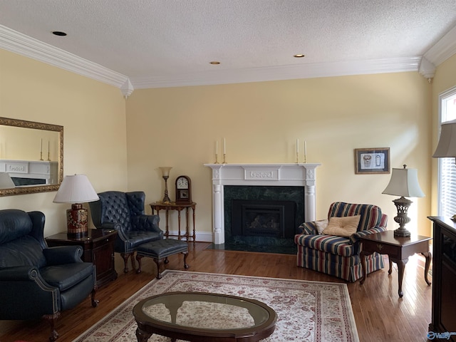 living room with a textured ceiling, ornamental molding, a premium fireplace, and wood finished floors