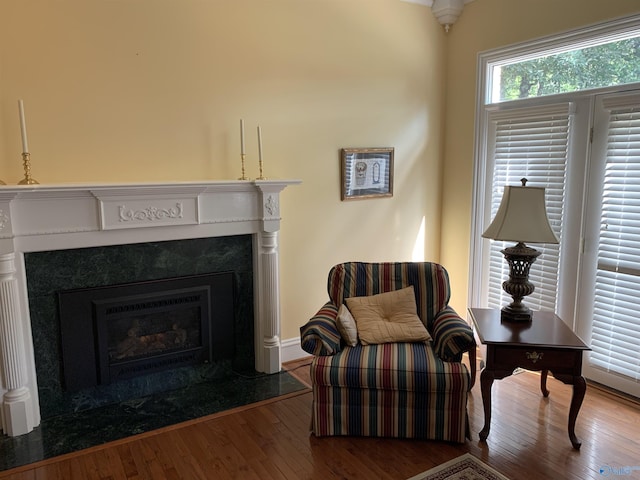 sitting room featuring a high end fireplace and hardwood / wood-style flooring