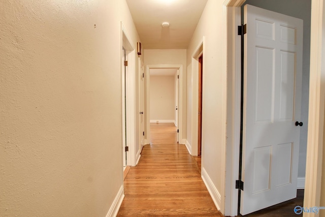 hall with baseboards and light wood-type flooring