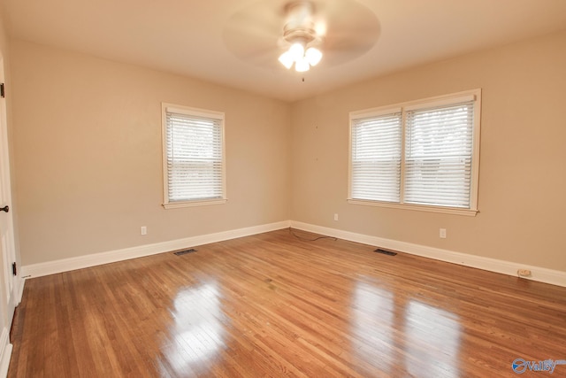 empty room featuring baseboards, visible vents, a ceiling fan, and wood finished floors