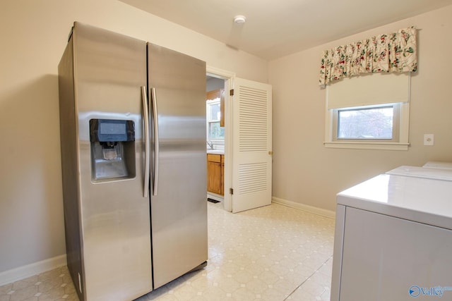 laundry room with baseboards, washing machine and clothes dryer, laundry area, and light floors