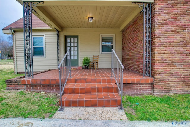 property entrance with a porch and brick siding