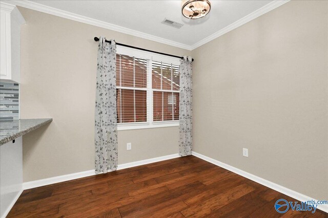 unfurnished dining area with visible vents, baseboards, wood finished floors, and crown molding