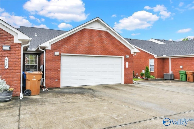 view of front of home featuring an attached garage, aphalt driveway, brick siding, and central air condition unit