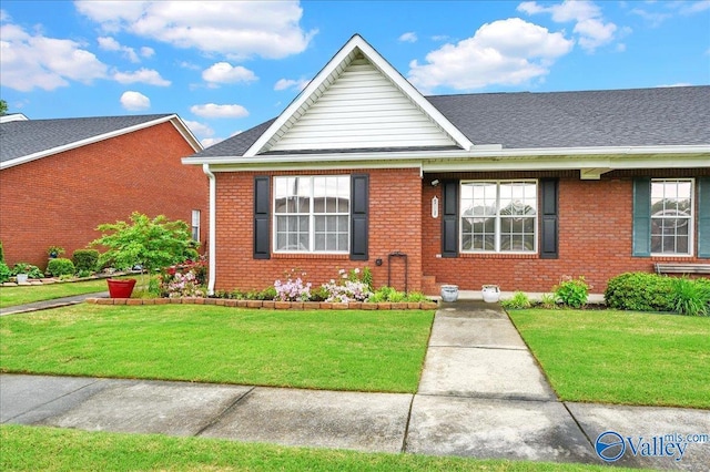 ranch-style house featuring brick siding, a shingled roof, and a front yard