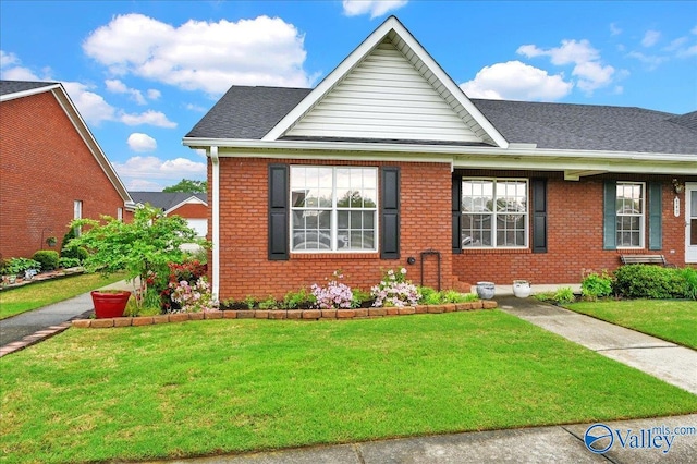view of front of house featuring brick siding, roof with shingles, and a front yard