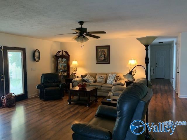 living room with ceiling fan, dark hardwood / wood-style floors, and a textured ceiling