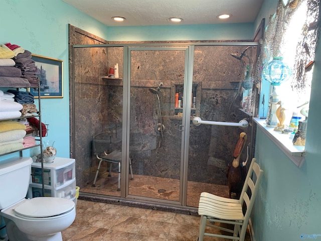 bathroom featuring a shower with shower door and toilet