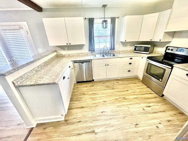 kitchen with premium range hood, appliances with stainless steel finishes, sink, white cabinets, and hanging light fixtures