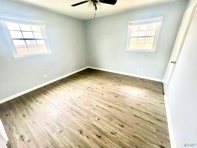 spare room with ceiling fan, plenty of natural light, and wood-type flooring