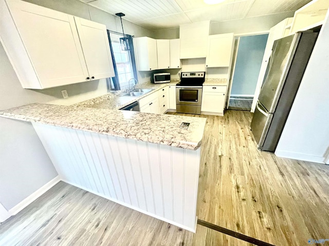 kitchen featuring sink, appliances with stainless steel finishes, pendant lighting, light hardwood / wood-style floors, and white cabinets