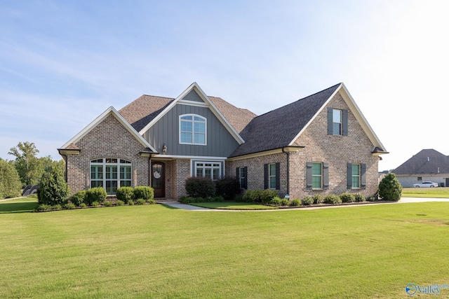 craftsman-style house featuring board and batten siding, brick siding, a front lawn, and roof with shingles