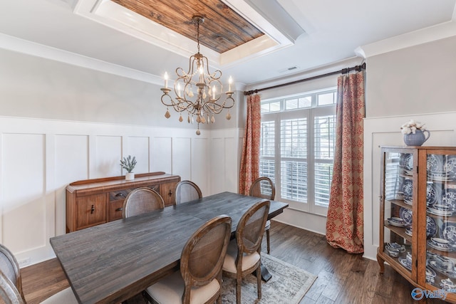 dining area with wainscoting, dark wood-style floors, a tray ceiling, crown molding, and a notable chandelier