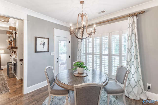 dining area with a notable chandelier, crown molding, and hardwood / wood-style flooring