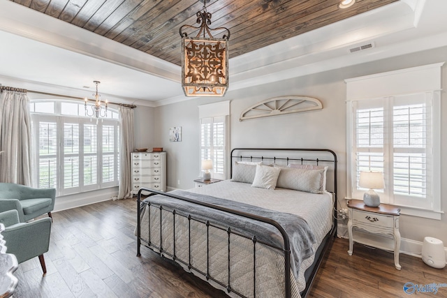 bedroom with dark hardwood / wood-style flooring, a notable chandelier, a raised ceiling, and ornamental molding