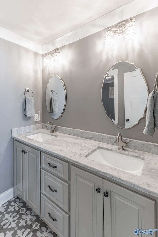 full bath with double vanity, a sink, and baseboards