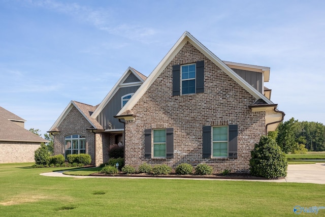 view of front of home with board and batten siding, brick siding, and a front lawn