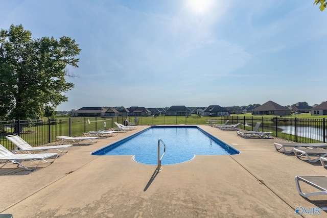 pool with a patio, a water view, fence, and a residential view