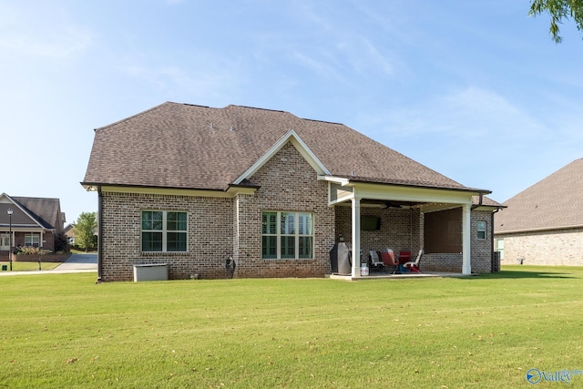 back of house featuring roof with shingles, a lawn, and brick siding