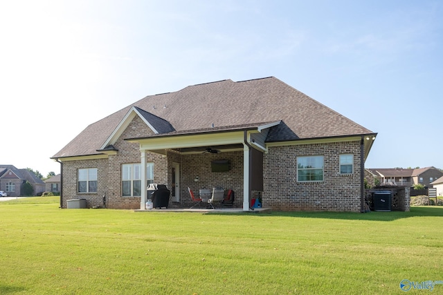 back of house featuring a patio, ceiling fan, roof with shingles, a yard, and brick siding