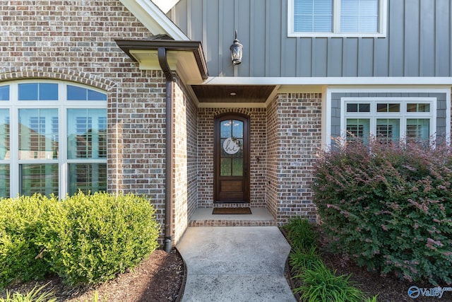 view of exterior entry with board and batten siding and brick siding