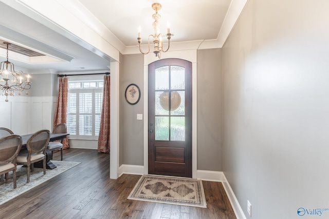 foyer entrance with dark wood-style floors, arched walkways, ornamental molding, and an inviting chandelier